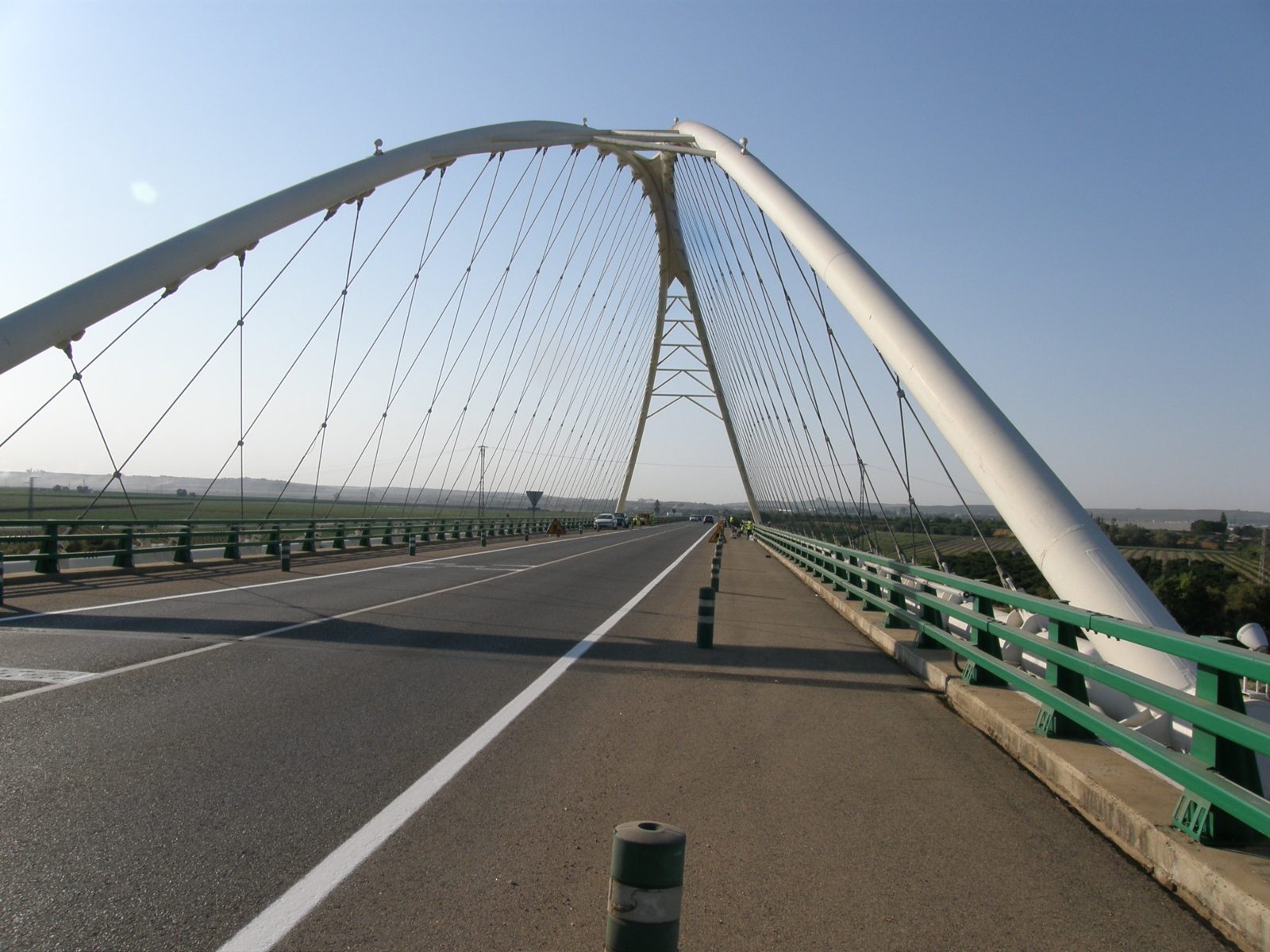 Calzada del puente con el arco blanco y los tirantes al fondo