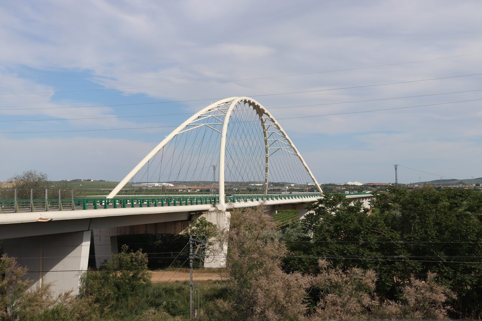 Vista lateral del puente en arco blanco sobre el río, con los pilares y el tablero